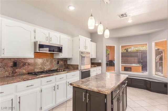kitchen featuring visible vents, white cabinetry, decorative backsplash, light stone counters, and appliances with stainless steel finishes