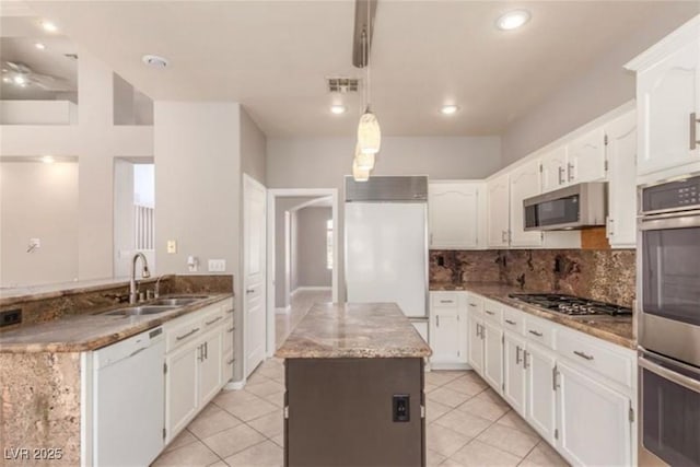 kitchen with white cabinets, a center island, a sink, tasteful backsplash, and appliances with stainless steel finishes