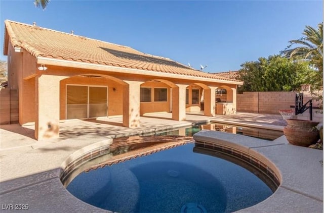 rear view of house featuring a fenced in pool, a tile roof, a patio, and stucco siding