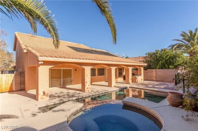 rear view of house with a fenced backyard, a tiled roof, stucco siding, a patio area, and a pool with connected hot tub