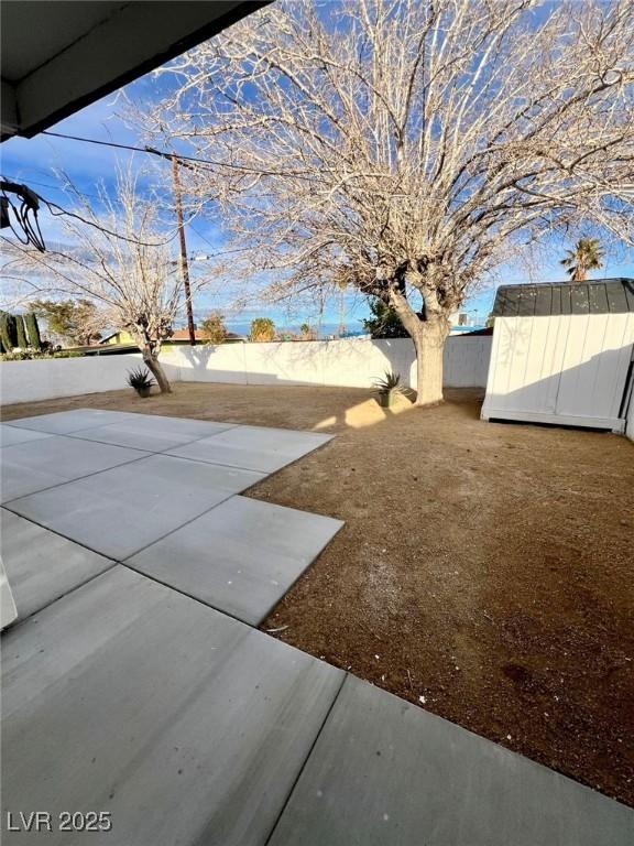 view of yard featuring a storage shed, a patio area, an outbuilding, and a fenced backyard