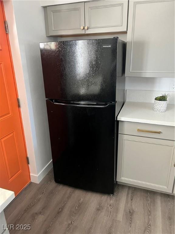 details with light countertops, gray cabinets, freestanding refrigerator, light wood-style floors, and baseboards