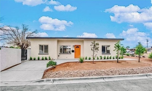 view of front of house with driveway, a gate, and stucco siding