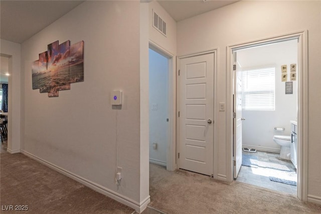 corridor featuring baseboards, visible vents, and carpet