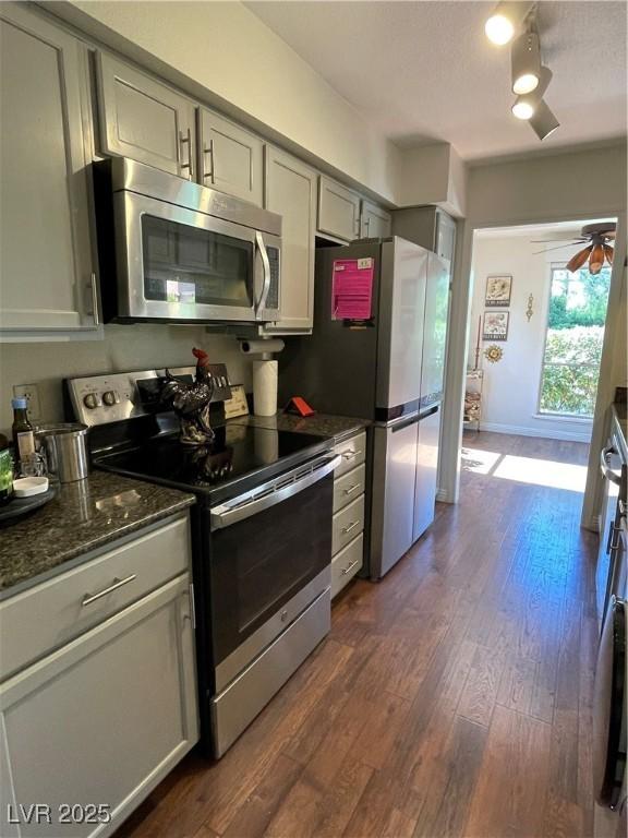 682 Oakmont Ave Unit 1507, Las Vegas, NV 89109 - kitchen with appliances with stainless steel finishes, dark wood-style floors, ceiling fan, dark stone counters, and gray cabinetry