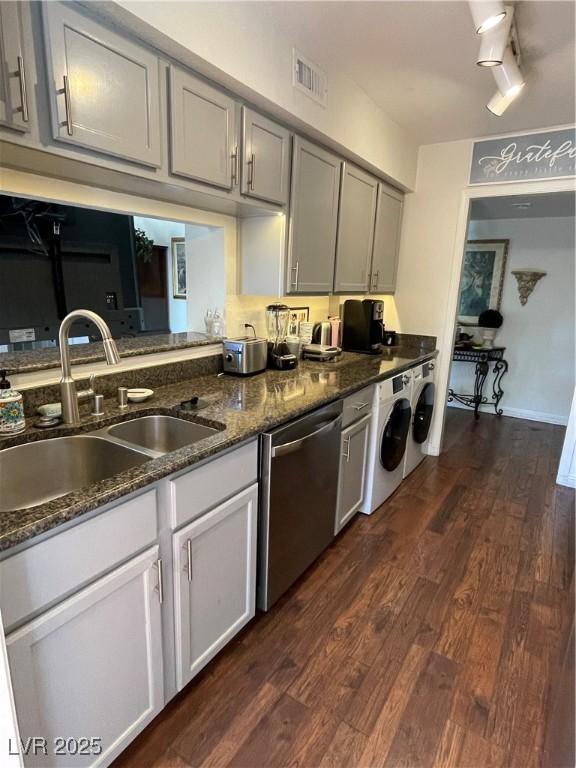 682 Oakmont Ave Unit 1507, Las Vegas, NV 89109 - kitchen with stainless steel dishwasher, dark wood-type flooring, washing machine and clothes dryer, and dark stone countertops