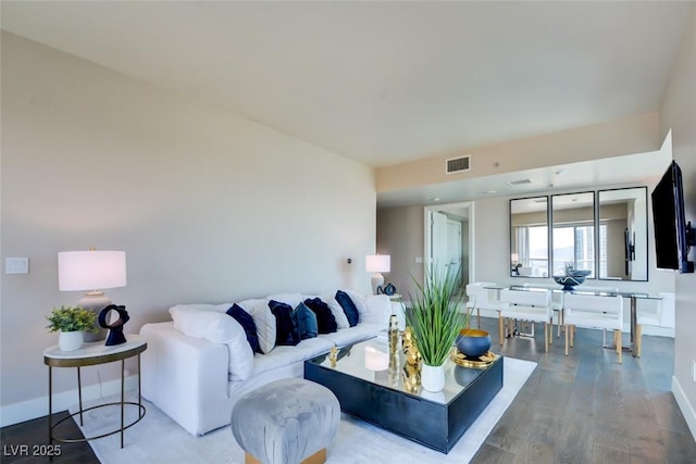 living room with visible vents, baseboards, and wood finished floors