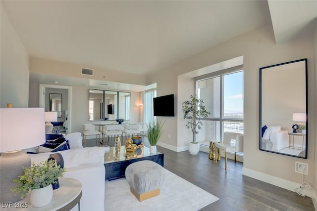 living area featuring visible vents, baseboards, and wood finished floors