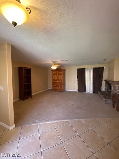 unfurnished living room with light tile patterned flooring, a textured ceiling, baseboards, and light carpet