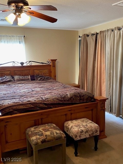 bedroom featuring ceiling fan, light carpet, and a textured ceiling