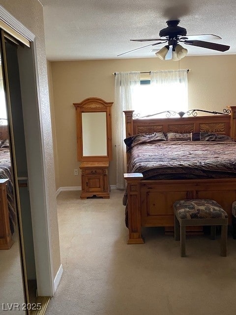 bedroom with light colored carpet, a ceiling fan, and a textured ceiling