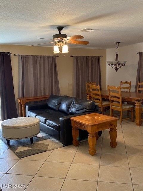 living room with ceiling fan, a textured ceiling, and light tile patterned floors