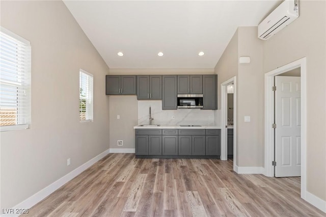 790 Lone Pine Rd, Pahrump, NV 89048 - kitchen with stainless steel microwave, an AC wall unit, gray cabinetry, light wood-style flooring, and lofted ceiling
