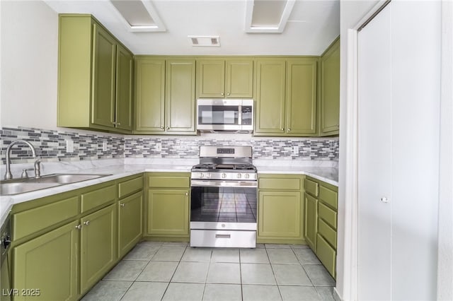 1400 Jamielinn Ln Unit 104, Las Vegas, NV 89110 - kitchen with stainless steel appliances, green cabinets, light countertops, light tile patterned floors, and backsplash