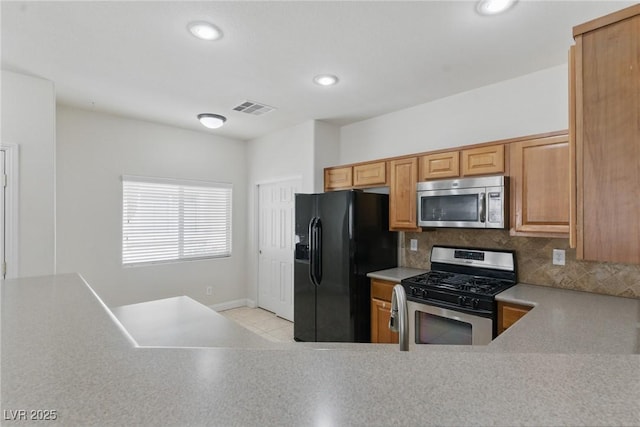 kitchen featuring light countertops, decorative backsplash, stainless steel appliances, and visible vents