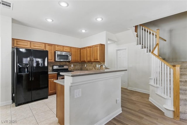kitchen featuring a peninsula, tasteful backsplash, baseboards, visible vents, and appliances with stainless steel finishes