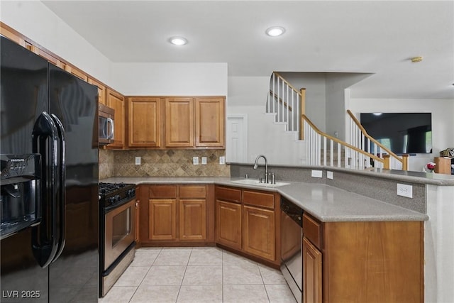 kitchen with a sink, brown cabinetry, decorative backsplash, stainless steel appliances, and a peninsula