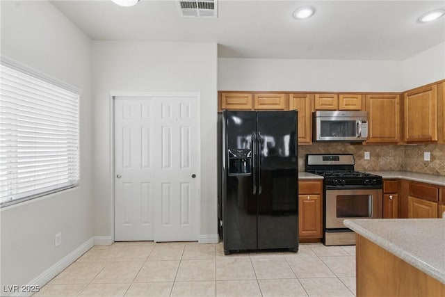kitchen featuring stainless steel appliances, light countertops, backsplash, visible vents, and light tile patterned flooring