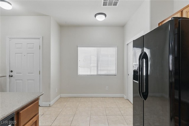 kitchen featuring light countertops, visible vents, light tile patterned floors, black refrigerator with ice dispenser, and brown cabinetry