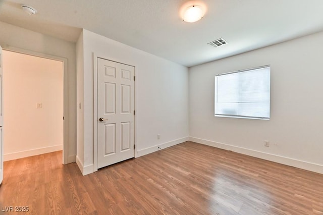 spare room with baseboards, light wood finished floors, and visible vents