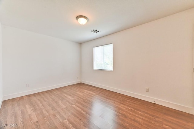 empty room featuring light wood-type flooring, visible vents, and baseboards