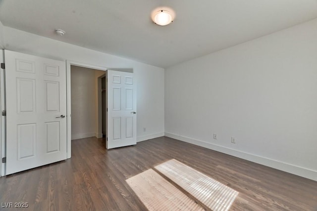 unfurnished bedroom with baseboards and dark wood-style floors