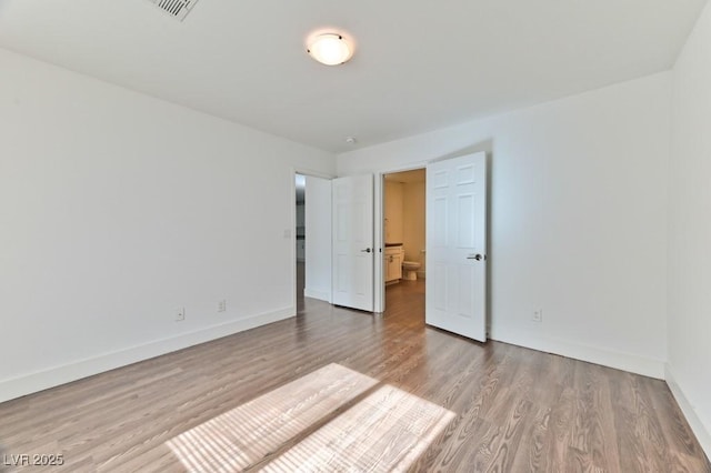 unfurnished bedroom featuring wood finished floors, visible vents, and baseboards