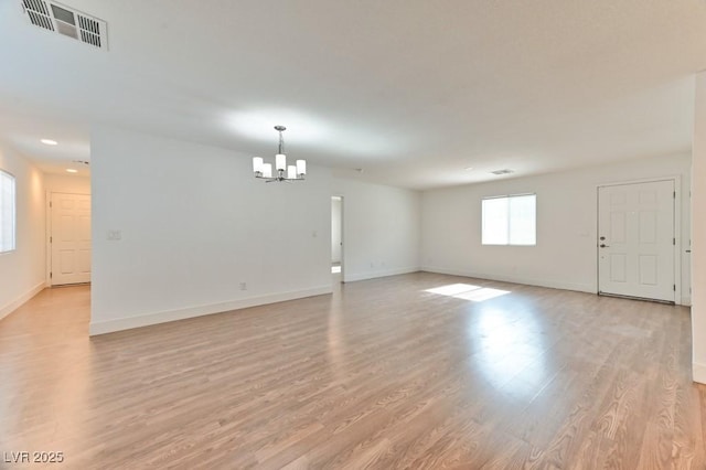 interior space featuring baseboards, light wood-style flooring, visible vents, and a chandelier