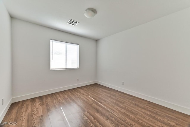 spare room featuring baseboards, wood finished floors, and visible vents