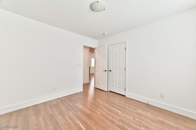 spare room featuring light wood-type flooring and baseboards