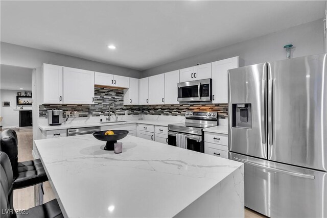 5208 Overland Ave, Las Vegas, NV 89107 - kitchen featuring appliances with stainless steel finishes, a sink, white cabinets, light stone countertops, and decorative backsplash