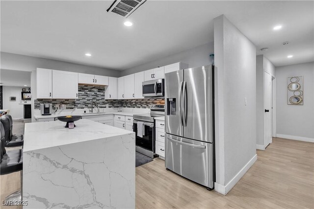 5208 Overland Ave, Las Vegas, NV 89107 - kitchen featuring appliances with stainless steel finishes, a sink, decorative backsplash, light wood finished floors, and recessed lighting