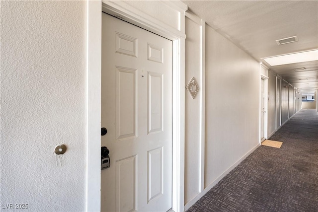 hallway featuring baseboards, visible vents, and carpet flooring
