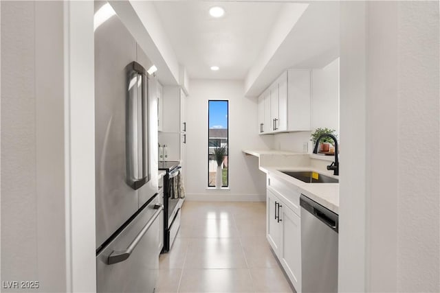 kitchen with white cabinets, stainless steel appliances, a sink, light countertops, and light tile patterned floors