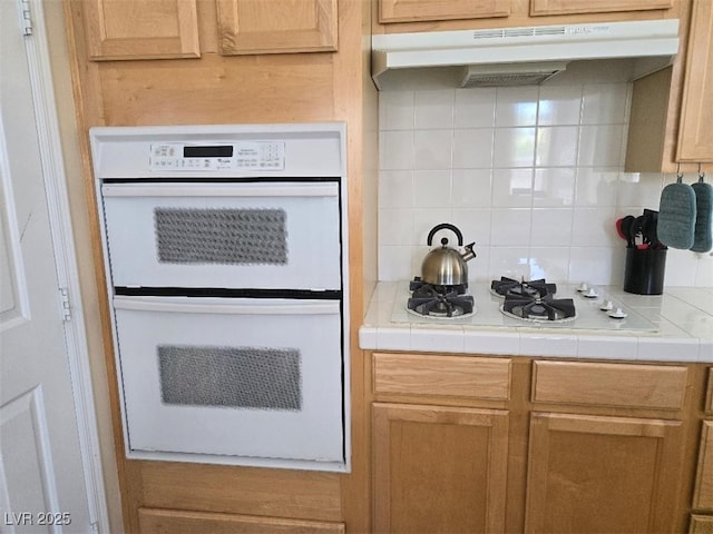 9324 Pitching Wedge Dr, Las Vegas, NV 89134 - kitchen featuring tile countertops, backsplash, under cabinet range hood, and white appliances