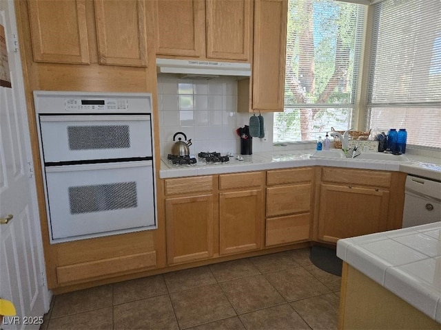 9324 Pitching Wedge Dr, Las Vegas, NV 89134 - kitchen with white appliances, tile patterned floors, under cabinet range hood, a sink, and tile countertops