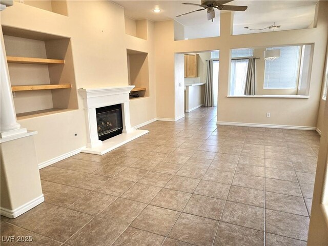 9324 Pitching Wedge Dr, Las Vegas, NV 89134 - unfurnished living room with a ceiling fan, built in shelves, tile patterned flooring, a glass covered fireplace, and baseboards