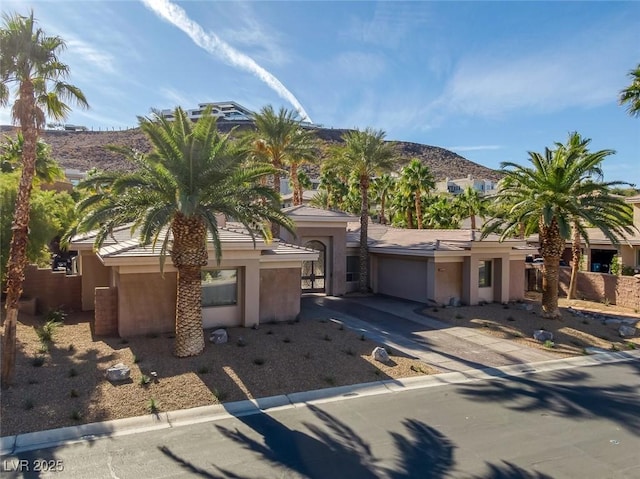 1665 Liege Dr, Henderson, NV 89012 - view of front facade featuring a garage, driveway, stucco siding, and a mountain view