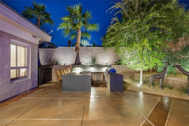 1665 Liege Dr, Henderson, NV 89012 - patio at night featuring fence, an outdoor kitchen, and area for grilling