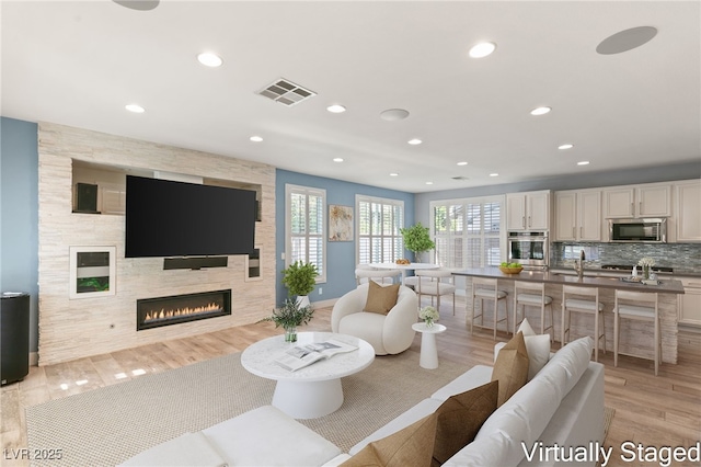 11784 Golden Moments Ave, Las Vegas, NV 89138 - living area featuring light wood-type flooring, visible vents, a large fireplace, and recessed lighting