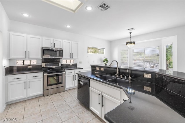 kitchen with dark countertops, a sink, stainless steel appliances, white cabinetry, and visible vents