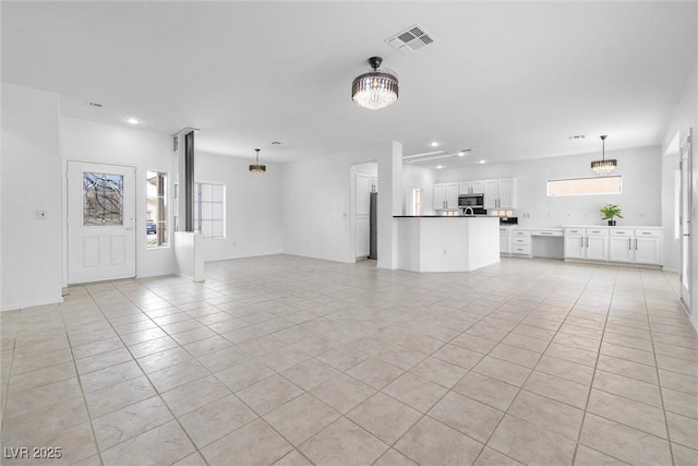 unfurnished living room with plenty of natural light, visible vents, recessed lighting, and a notable chandelier