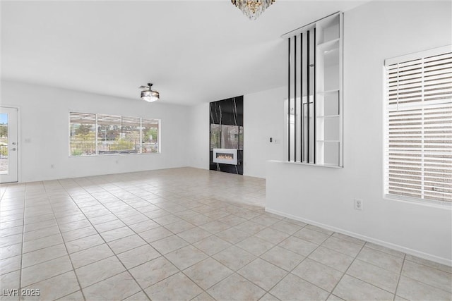 unfurnished living room featuring a fireplace, a notable chandelier, and light tile patterned floors