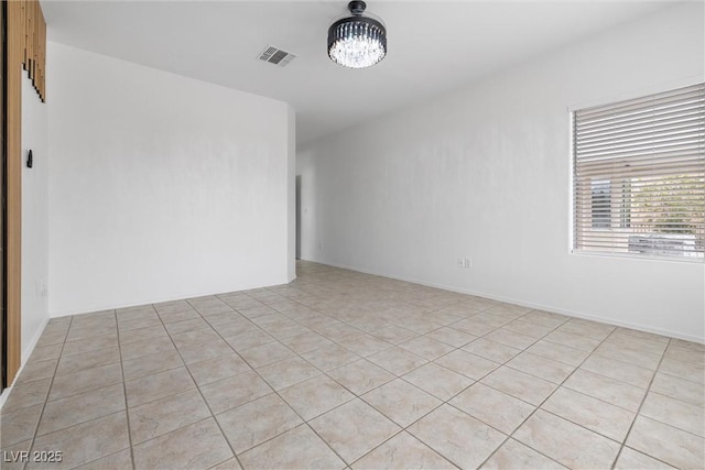 unfurnished room with a notable chandelier, visible vents, and light tile patterned floors