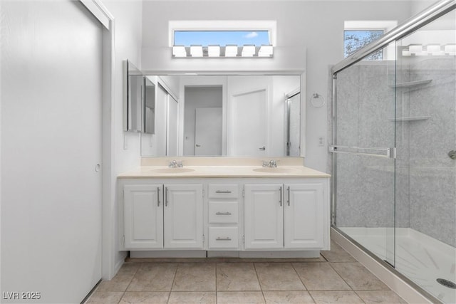 bathroom featuring double vanity, a shower stall, tile patterned floors, and a sink