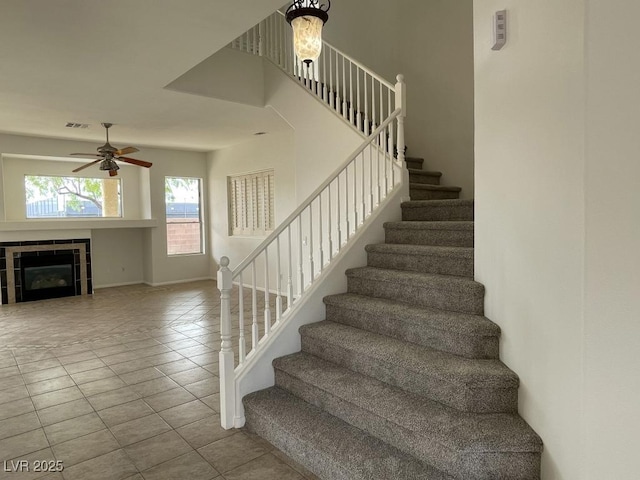 825 Happy Sparrow Ave, Henderson, NV 89052 - staircase featuring a tile fireplace, tile patterned floors, visible vents, a ceiling fan, and baseboards