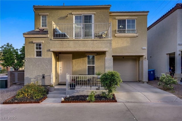 view of property featuring a garage, a balcony, stucco siding, concrete driveway, and a porch