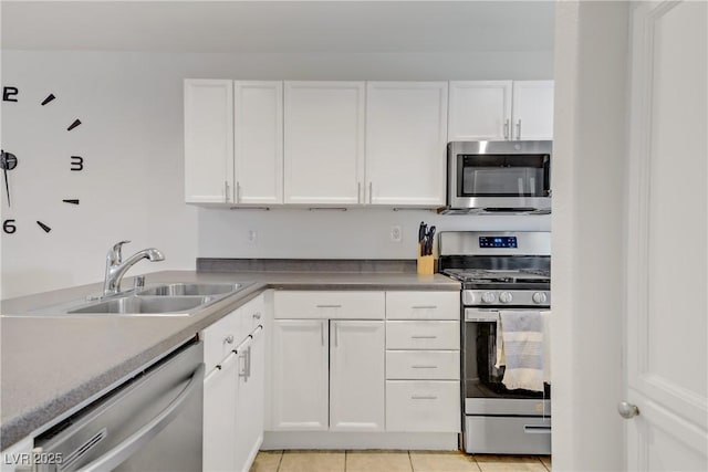 kitchen featuring a sink, light tile patterned floors, stainless steel appliances, and white cabinetry