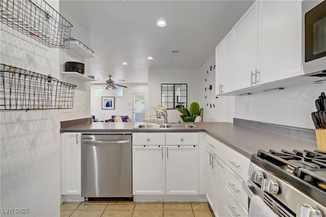 kitchen featuring white cabinets, a sink, stainless steel appliances, a ceiling fan, and light tile patterned floors