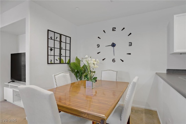 dining area featuring baseboards and light carpet